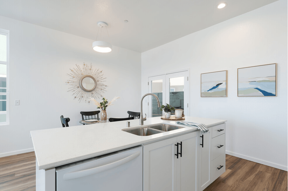 a kitchen with white cabinetry and a large white island with a stainless steel sink