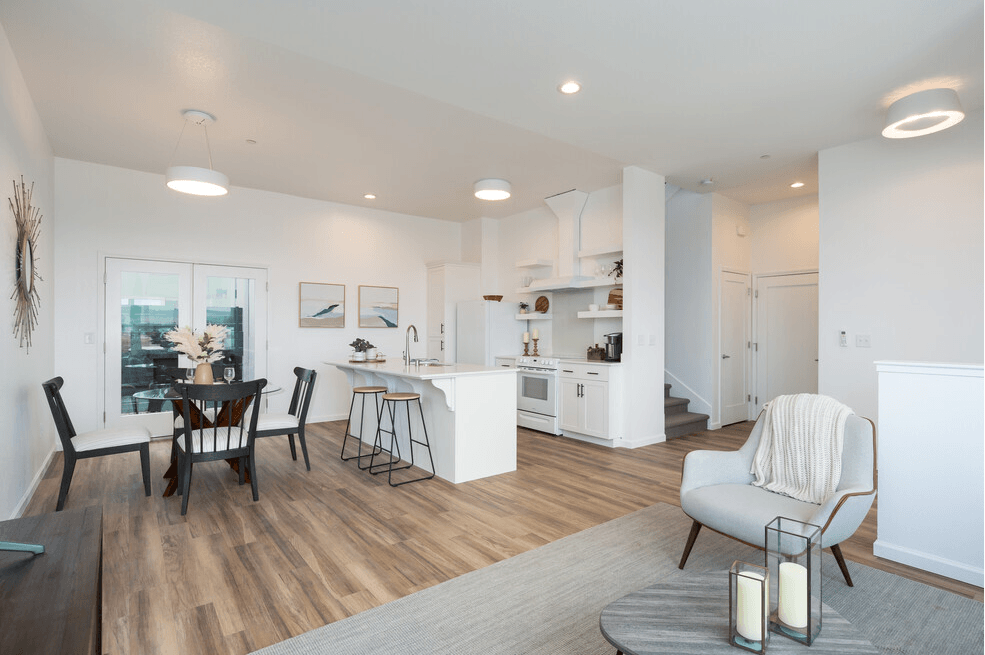 a living room and kitchen area with white walls and hardwood floors