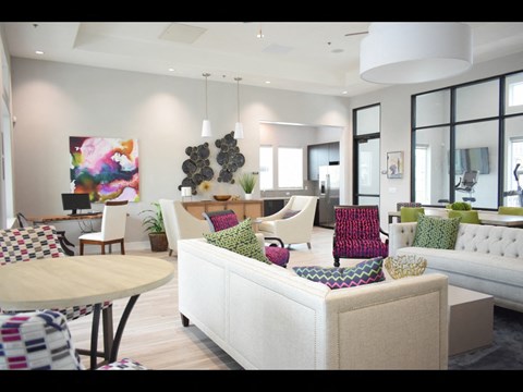A living room with a white couch and a painting on the wall.