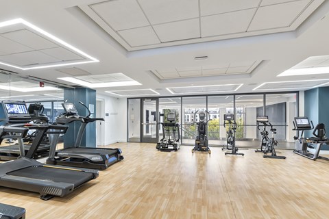 A gym with treadmills, elliptical machines, and other exercise equipment. at Trio Newton Apartments, Newton, Massachusetts