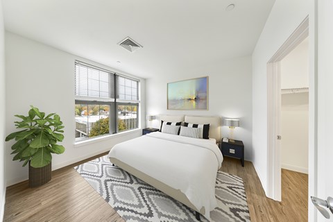 A bedroom with a large bed and a painting on the wall. at Trio Newton Apartments, Newton