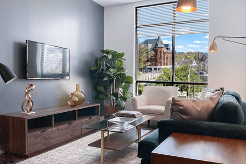 A living room with a green couch and a glass coffee table.