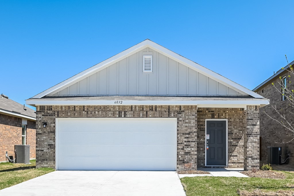 the front of a brick house with a white garage door