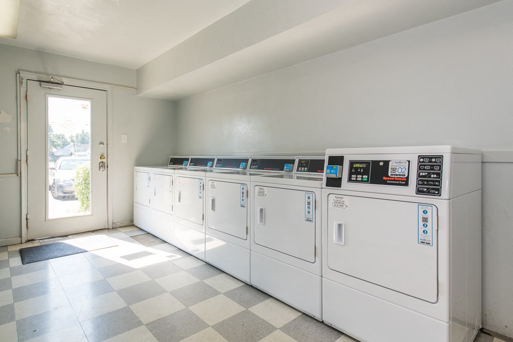a row of washers and dryers in the laundry room of an apartment building