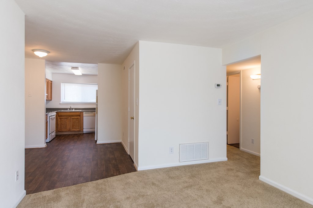 an empty living room with white walls and a kitchen