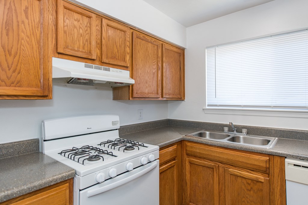a kitchen with a stove and sink and wooden cabinets