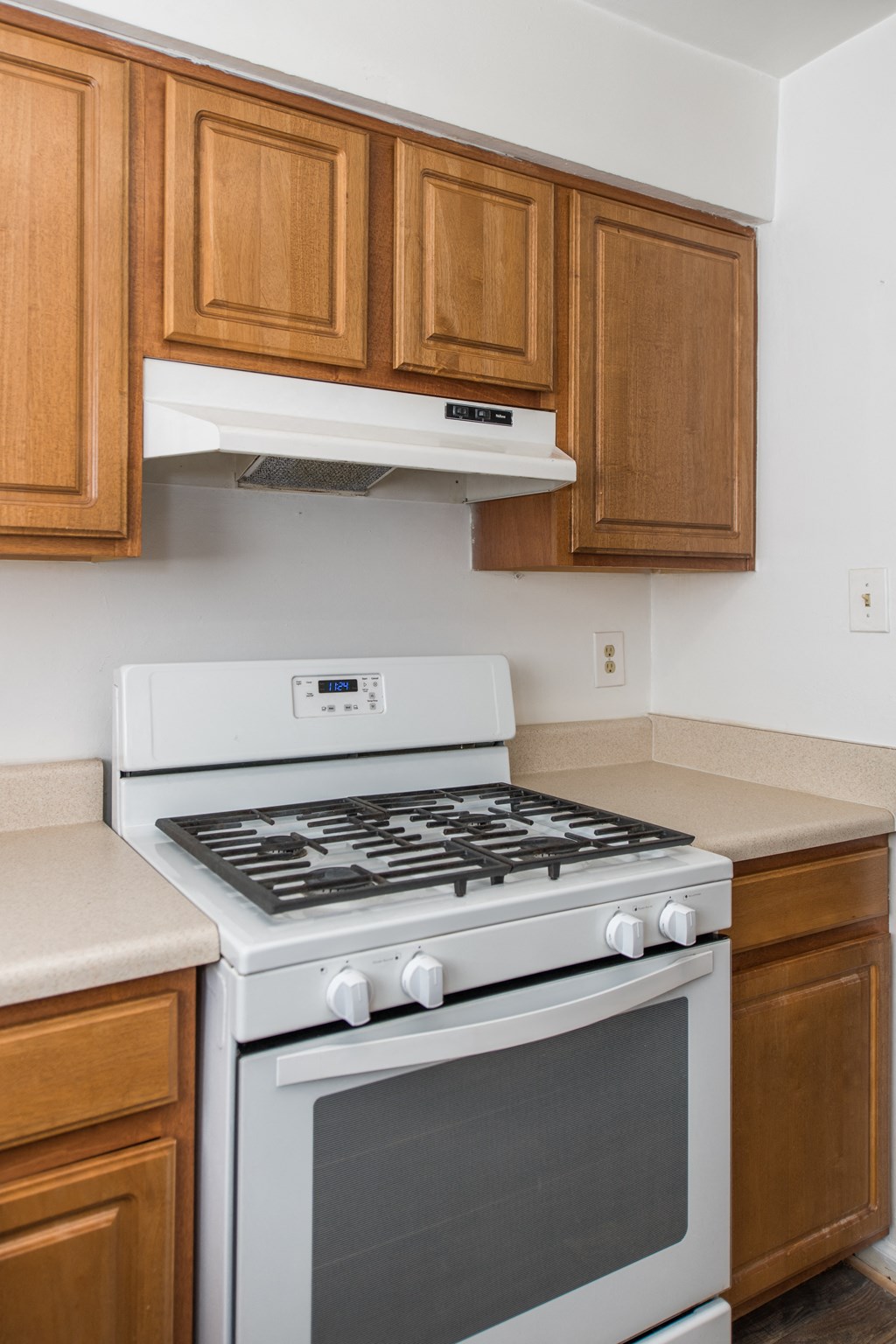 an empty kitchen with a white stove and oven and wooden cabinets