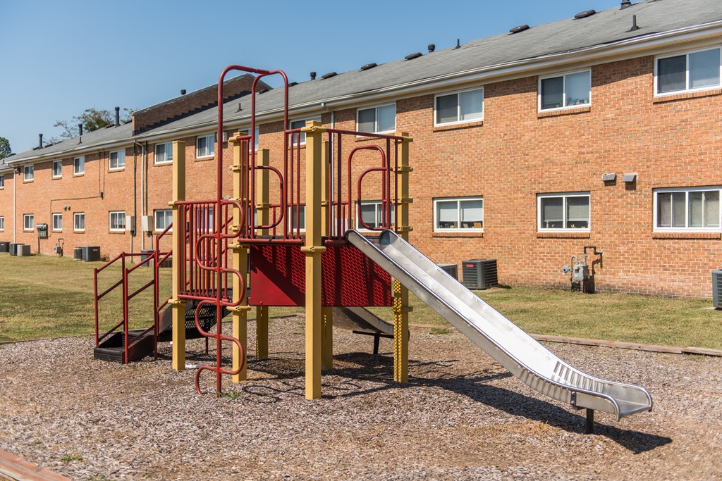 a slide in a playground in front of a brick building