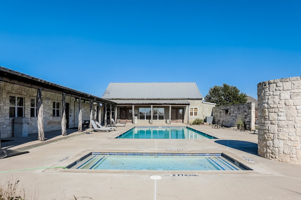 a swimming pool and pool house in front of a stone building