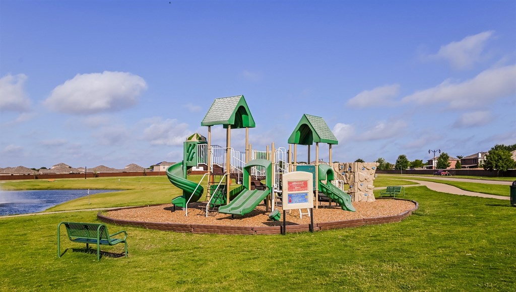 a playground with a large green playset in a park