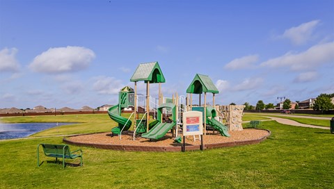 Forney, TX, House Rentals - Windmill Farms - Playground Near Pond With Slide Towers, Benches, and Surrounded By Manicured Grass Lawn.