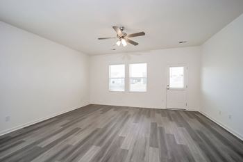 an empty living room with a ceiling fan and wood floors