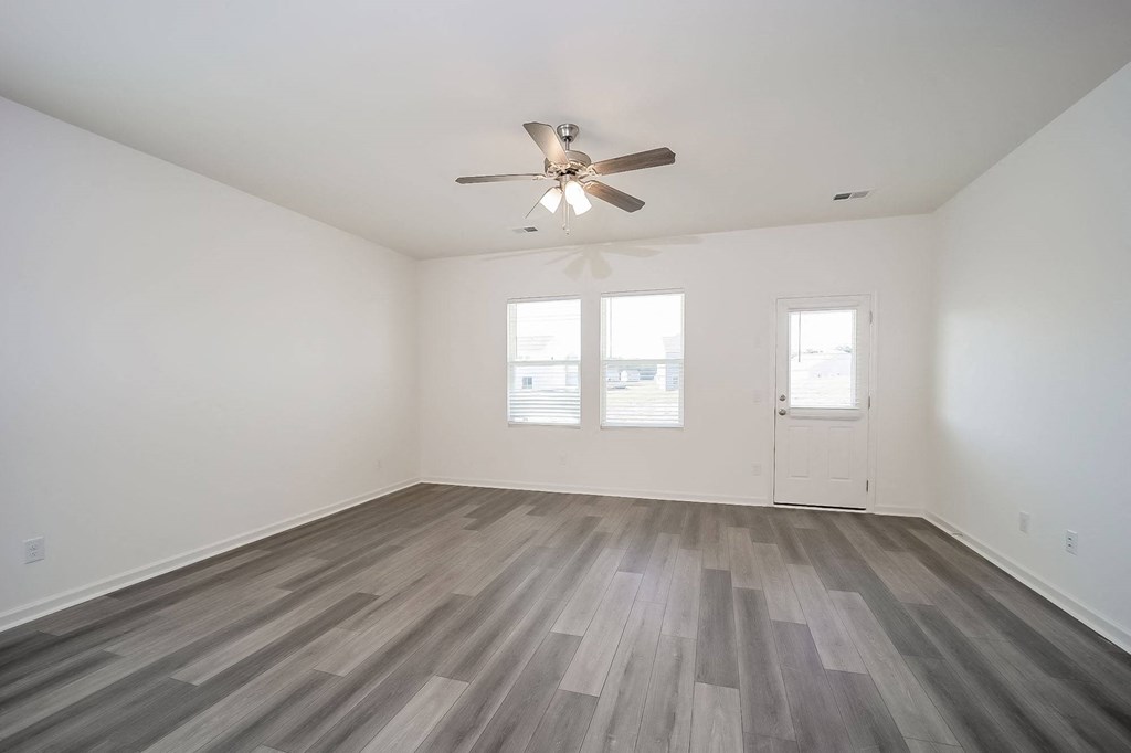 an empty living room with a ceiling fan and wood floors