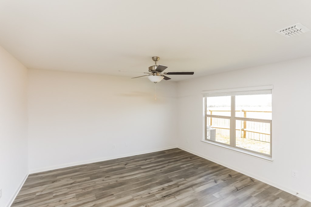 an empty room with a ceiling fan and a window