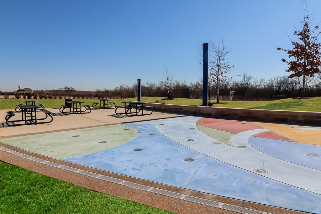 A playground with a colorful ground and a tall black pole.