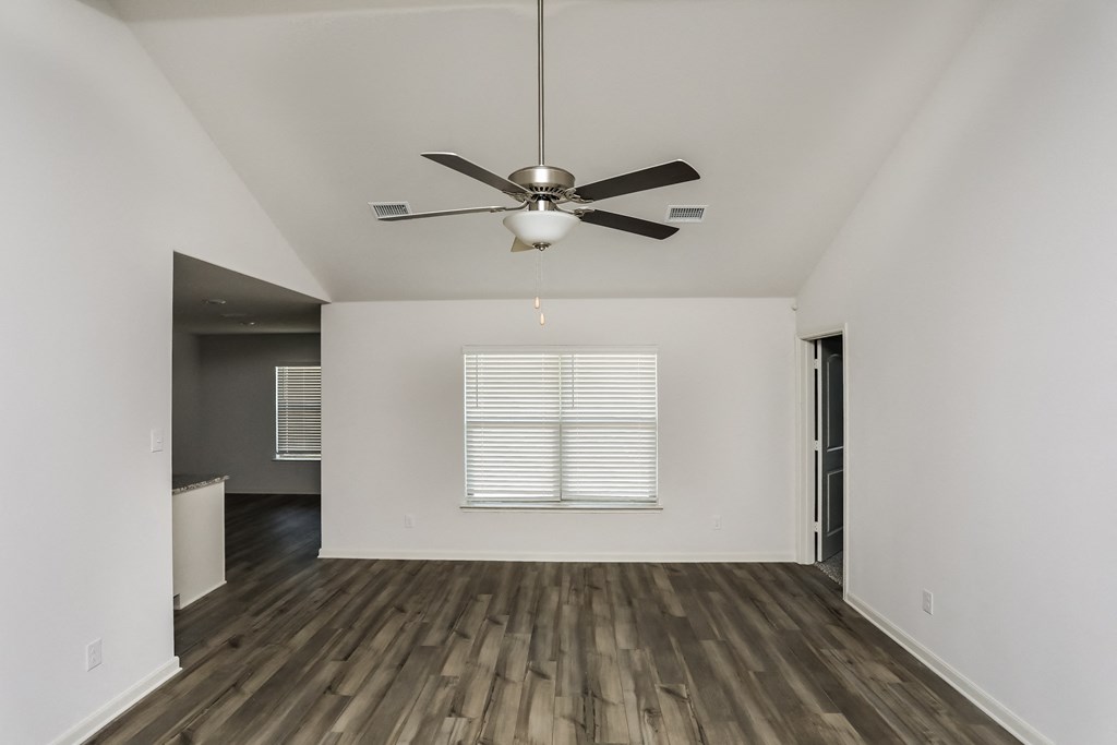 an empty living room with white walls and a ceiling fan