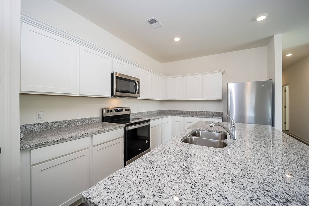 a kitchen with granite counter tops and a stainless steel refrigerator