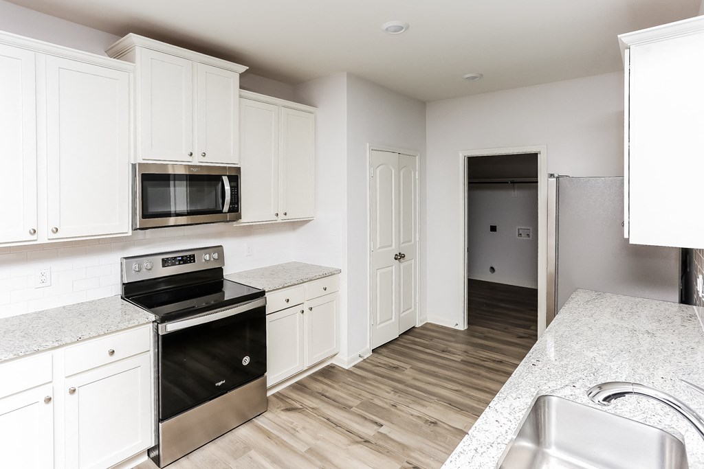 3 Bedroom Homes for rent in Crowley TX- Lasater Ranch - An interior shot of the kitchen, featuring stainless steel appliances, marble counter tops, and white cabinets