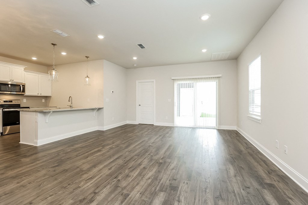 an empty living room and kitchen with wood flooring