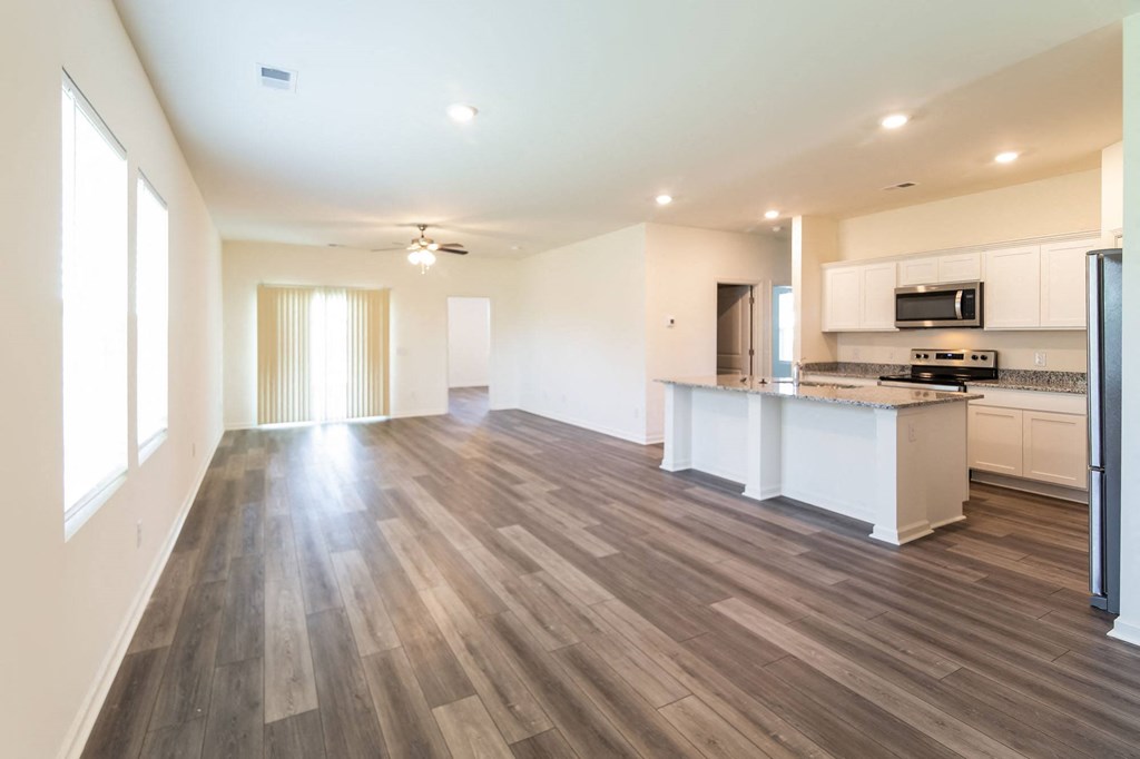 an empty living room and kitchen with wood flooring