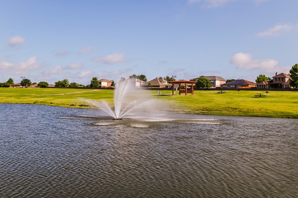 a fountain in the middle of a pond on a golf course