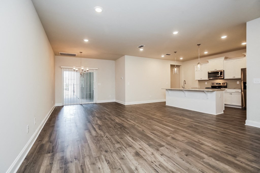 an empty living room and kitchen with wood flooring
