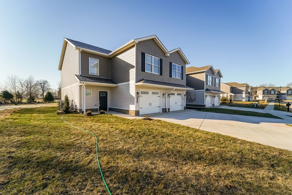 a beige house with a yard and a driveway
