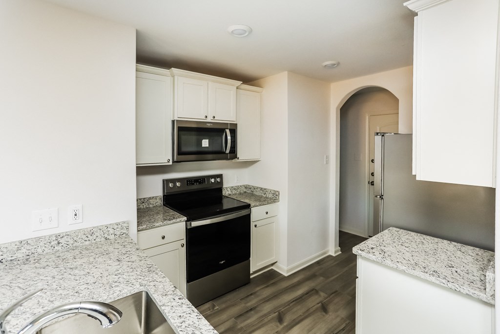 a kitchen with granite counter tops and white cabinets