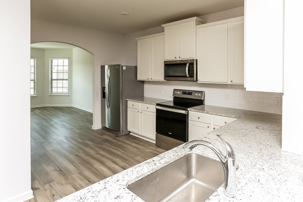 an empty kitchen with white cabinets and stainless steel appliances