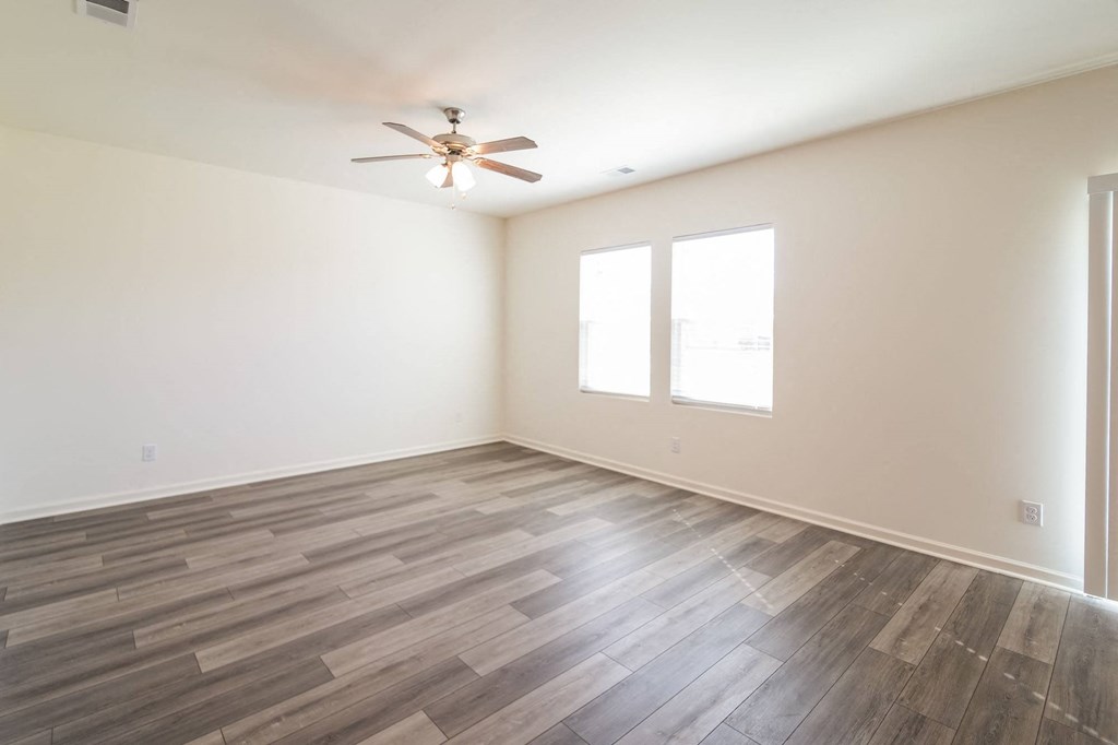 an empty living room with wood floors and a ceiling fan