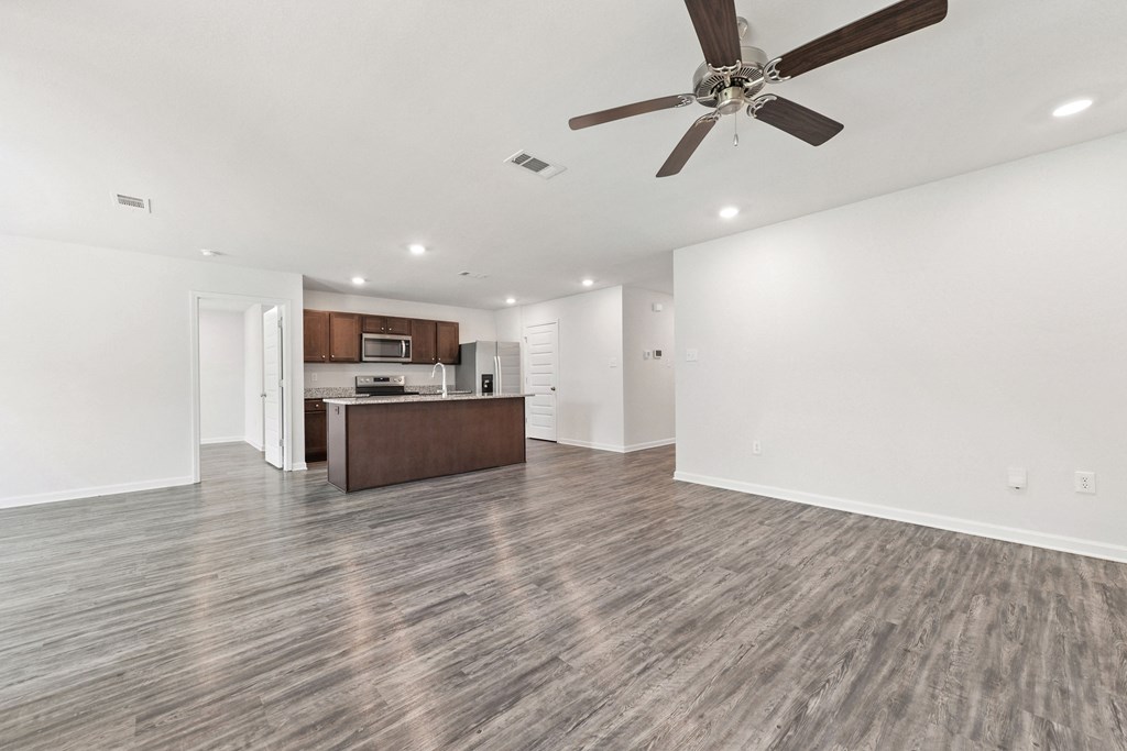 an empty living room and kitchen with a ceiling fan