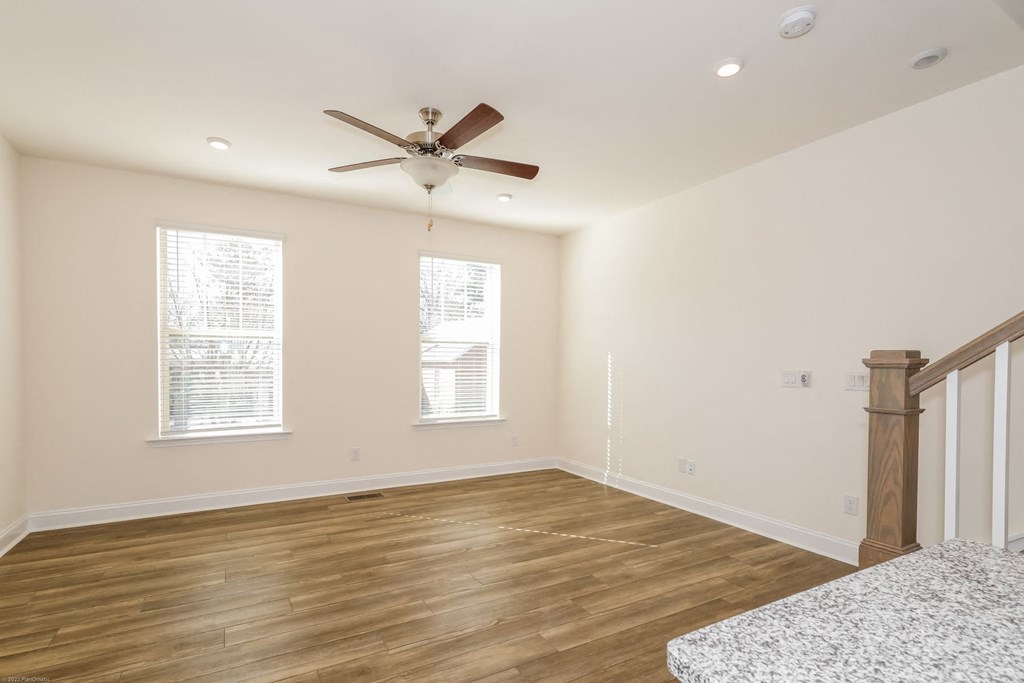 Townhomes for Rent in Charlotte - Loso Walk - Spacious Living Room with Wood-Style Flooring, Windows, Ceiling Fan, and Staircase
