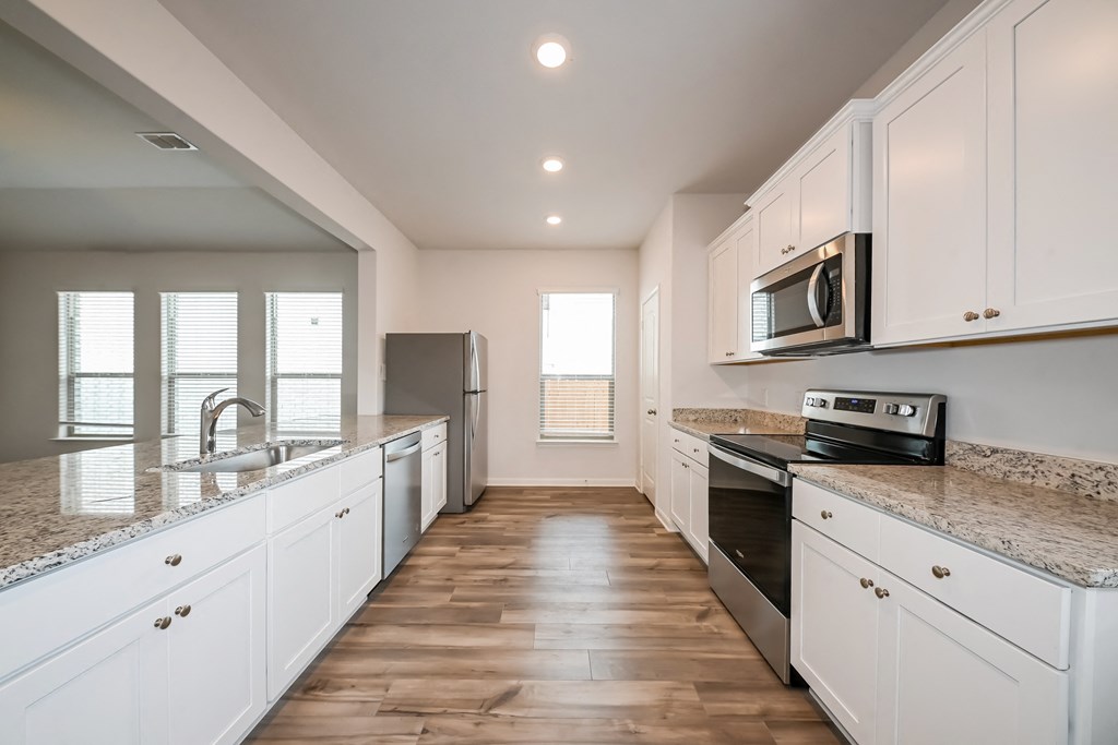 an empty kitchen with white cabinets and granite counter tops