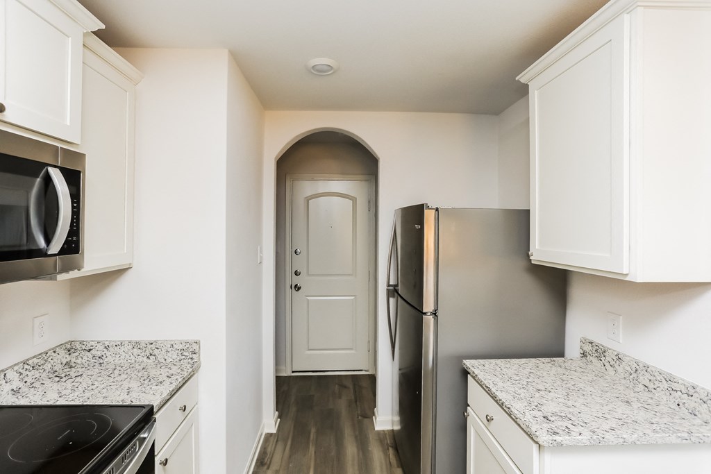 a kitchen with white cabinets and stainless steel appliances and a door