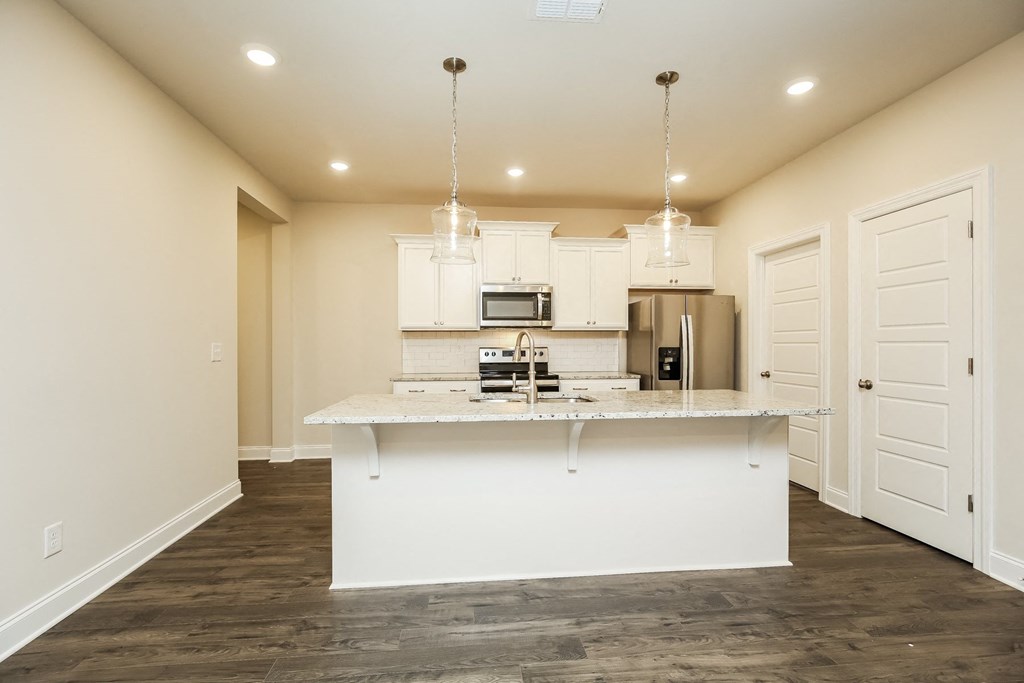 a kitchen with white cabinets and a marble counter top
