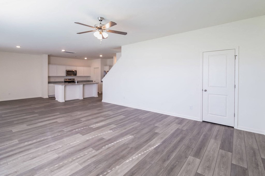 an empty living room and kitchen with a ceiling fan