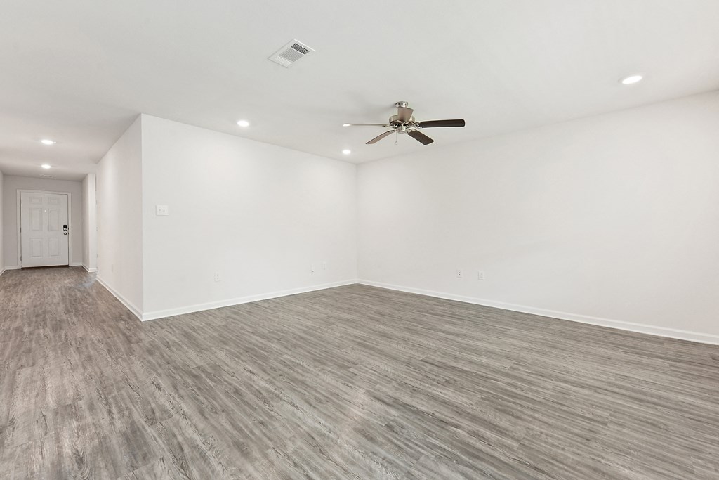 an empty living room with white walls and a ceiling fan