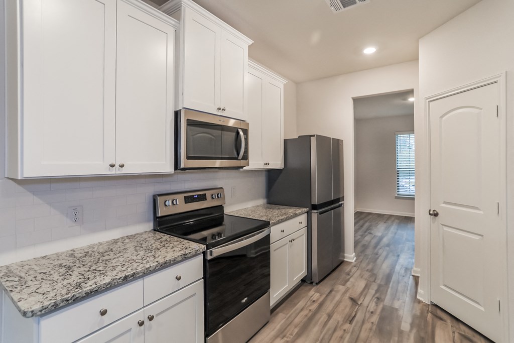 an empty kitchen with white cabinets and stainless steel appliances