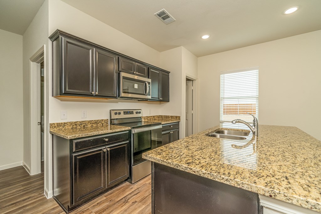 a kitchen with black cabinets and granite counter tops and a sink