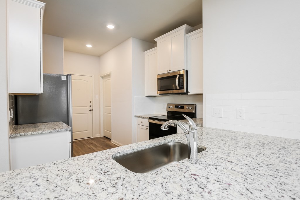 a kitchen with white cabinets and granite counter tops and a sink