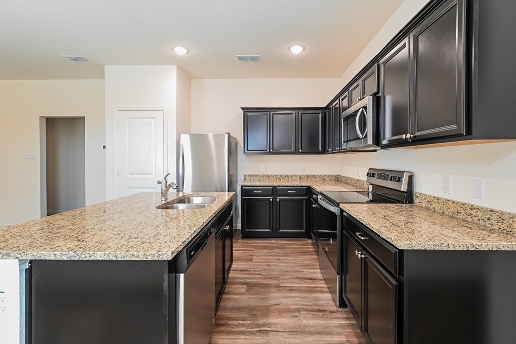 a kitchen with granite counter tops and black cabinets