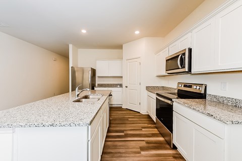 A kitchen with white cabinets and a granite countertop.