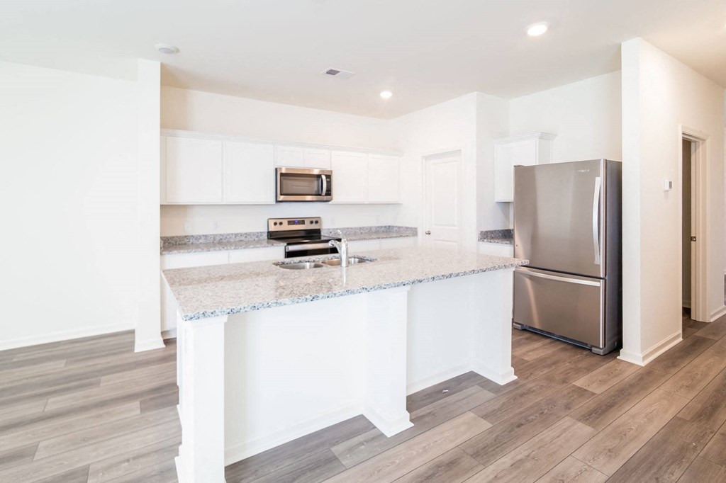 a kitchen with a marble counter top and a stainless steel refrigerator