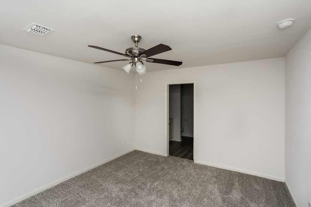 an empty room with a ceiling fan and a door to a hallway