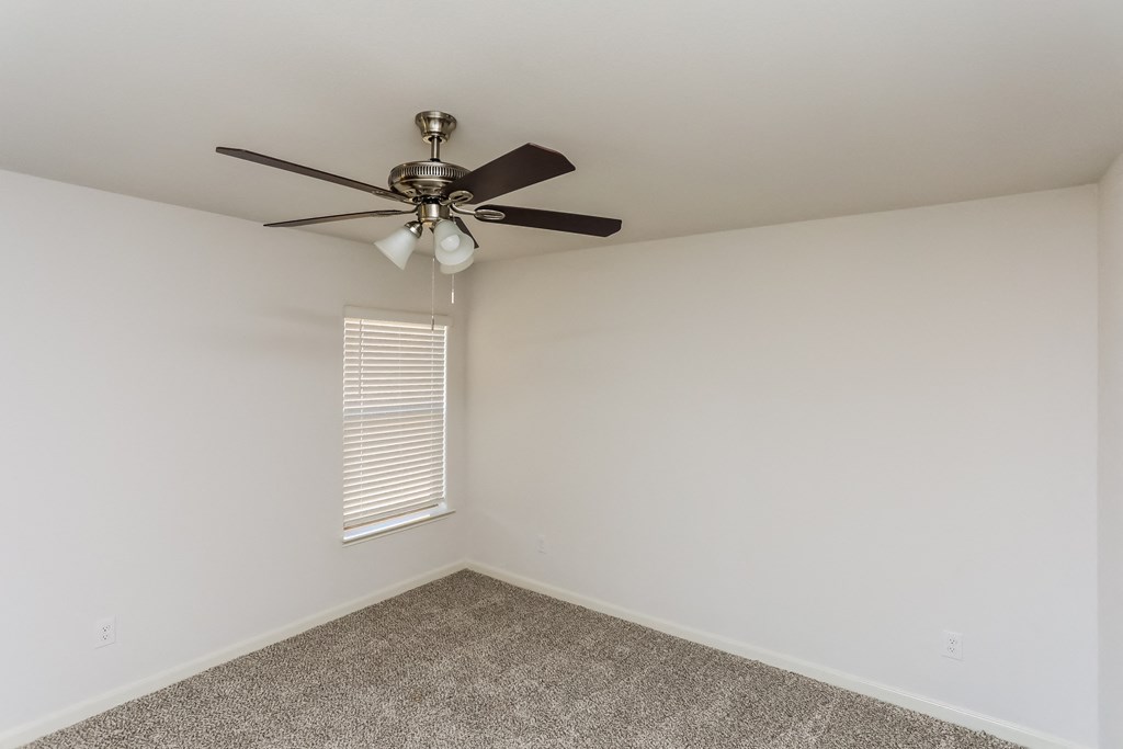 an empty room with a ceiling fan and a window
