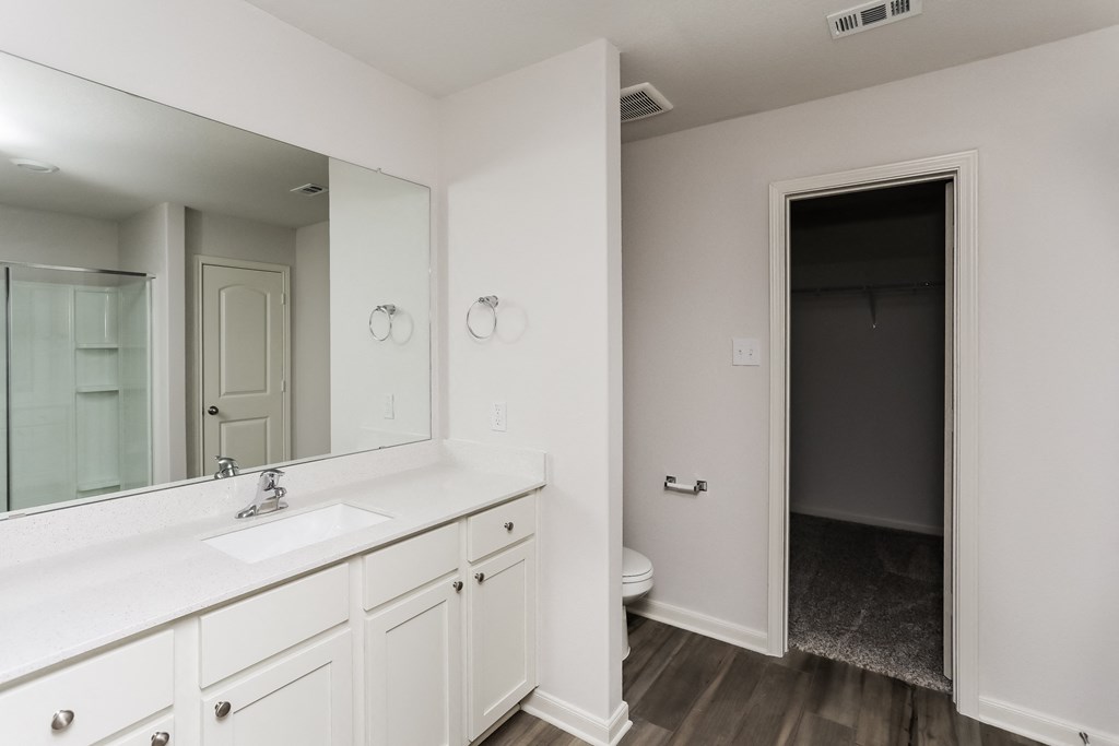 an empty bathroom with a large mirror and a white vanity with a sink and toilet