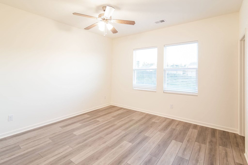 an empty living room with wood floors and a ceiling fan