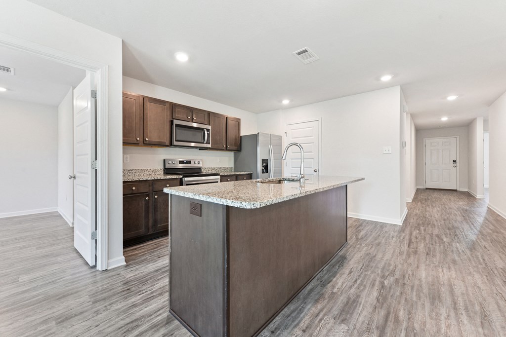 an open kitchen with a large island with granite counter top and