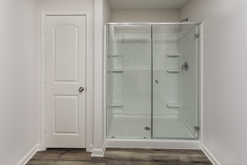 a walk in shower in a room with a white door