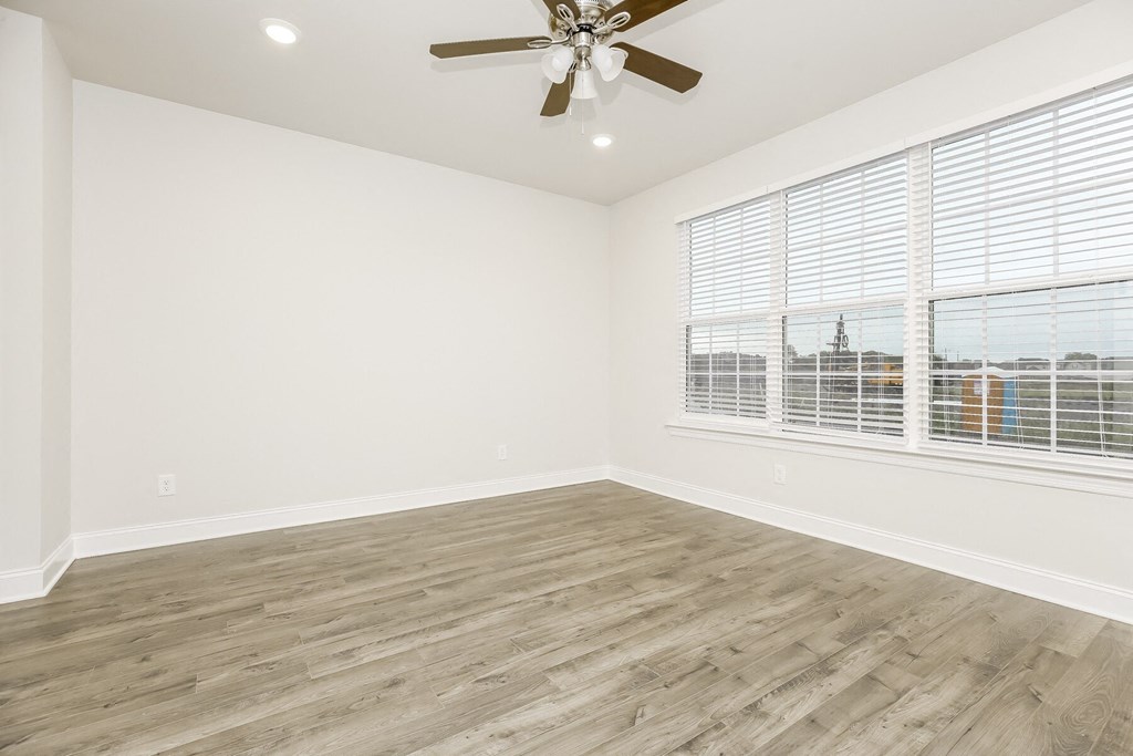 an empty living room with a ceiling fan and a window